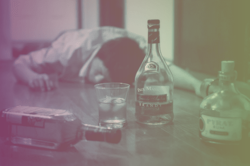 Пьяный мужчина спит на полу среди бутылок