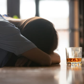 Мужчина лежит возле стакана алкоголя